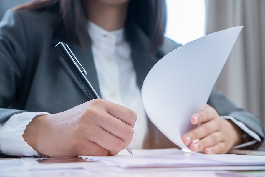 Businesswoman reviewing and signing accounting documents at a desk